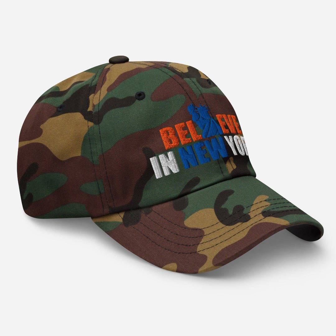 Left angle view of Believe in NYK camo trucker hat with orange and blue patches - Rebel P Customs